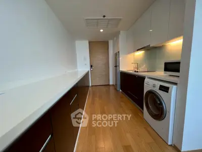 Modern kitchen with sleek cabinets, washing machine, and microwave in a stylish apartment.