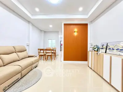 Spacious modern living room with elegant decor and dining area, featuring a cozy beige sofa and stylish lighting.