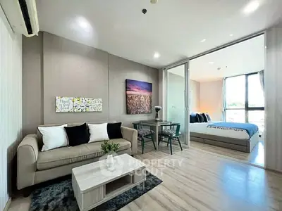 Modern open-plan living room with cozy seating and stylish decor adjacent to a bright bedroom.