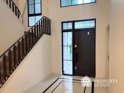 Elegant entrance with modern staircase and sleek black door in a stylish home