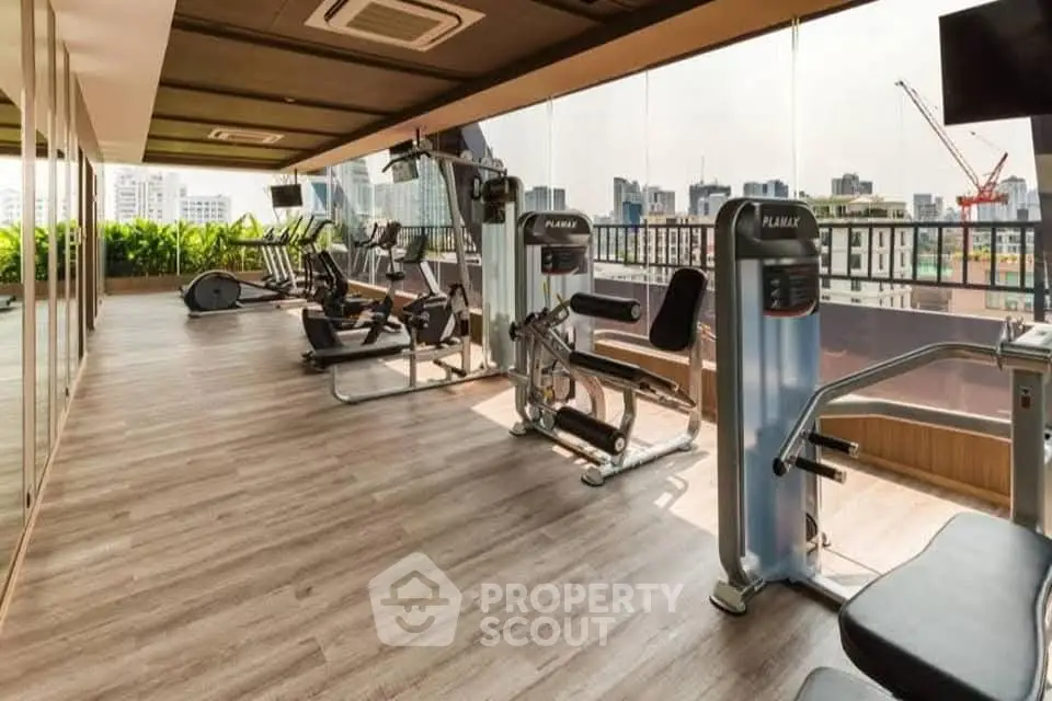 Spacious modern gym with city view in luxury apartment building.