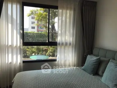 Cozy bedroom with large windows and elegant curtains offering a serene garden view.
