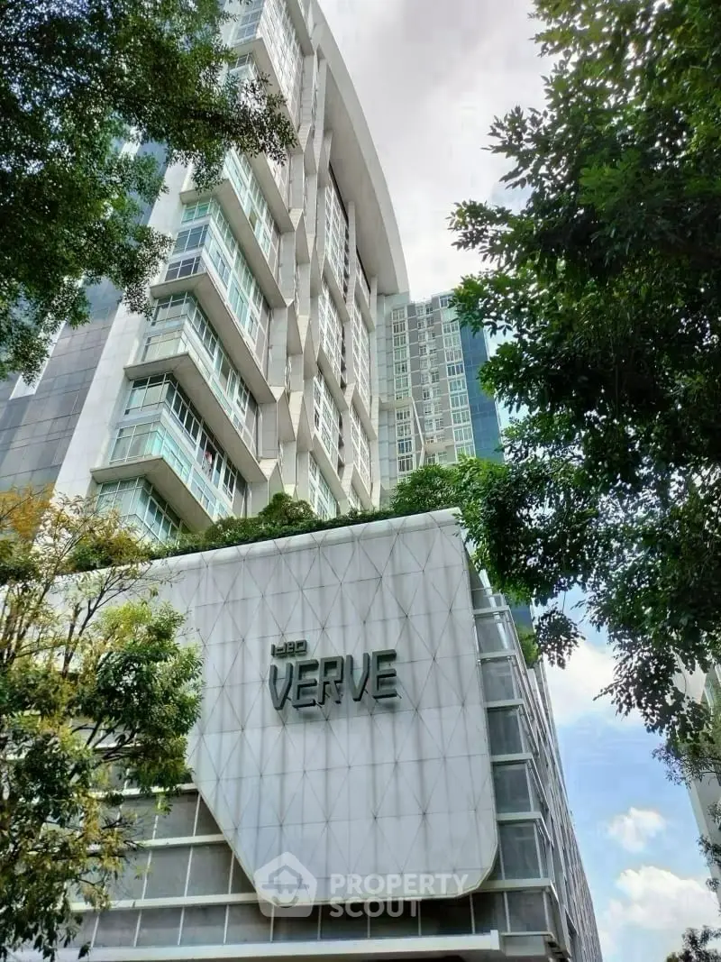 Modern high-rise building with unique architectural design and lush greenery.