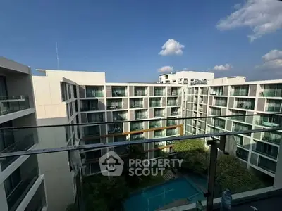 Modern apartment complex with pool view from balcony under clear blue sky.