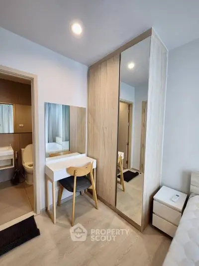Modern bedroom with sleek wardrobe and stylish vanity in a cozy apartment.