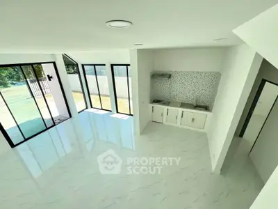 Spacious modern living room with open kitchen and large windows offering abundant natural light.