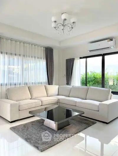 Elegant living room with modern L-shaped sofa and chic chandelier, offering a serene garden view.