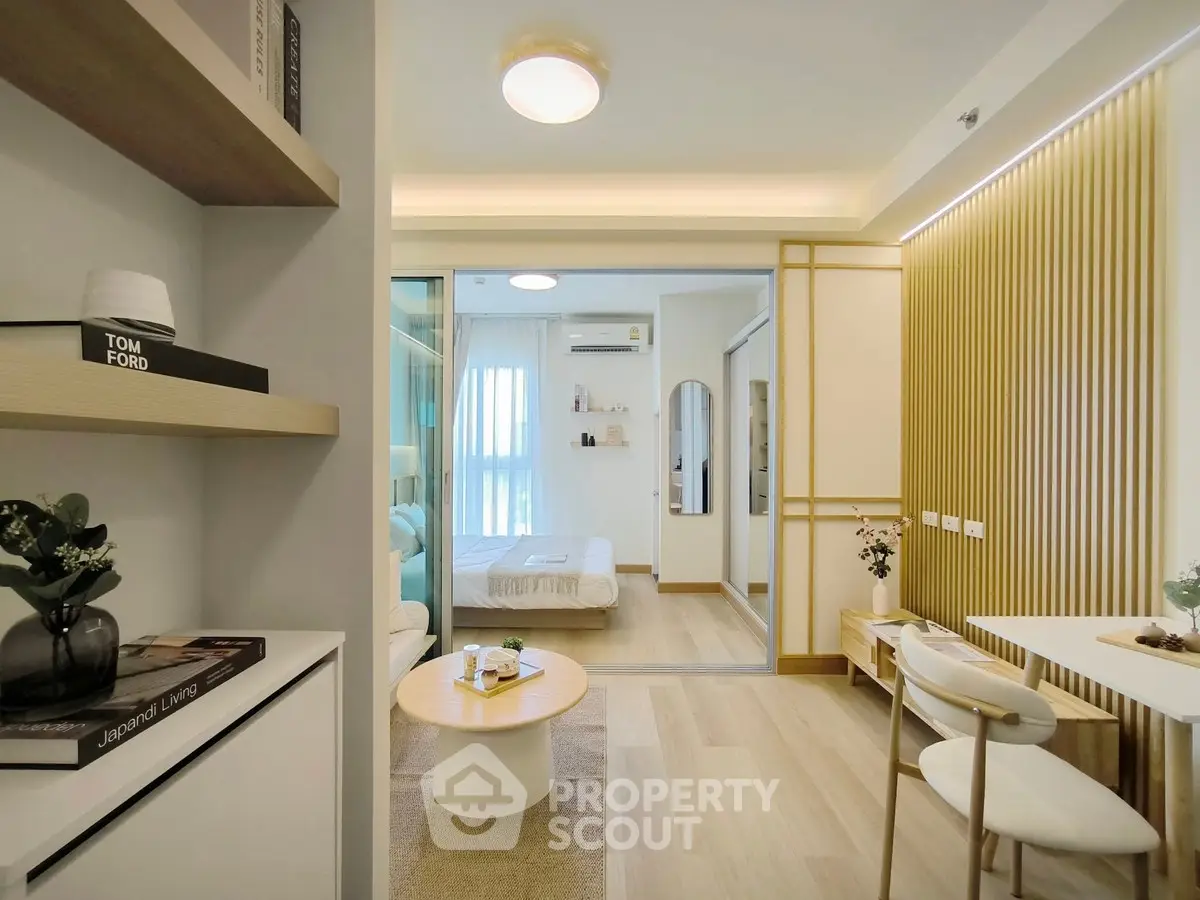 Modern open-plan living room with stylish decor and view into cozy bedroom