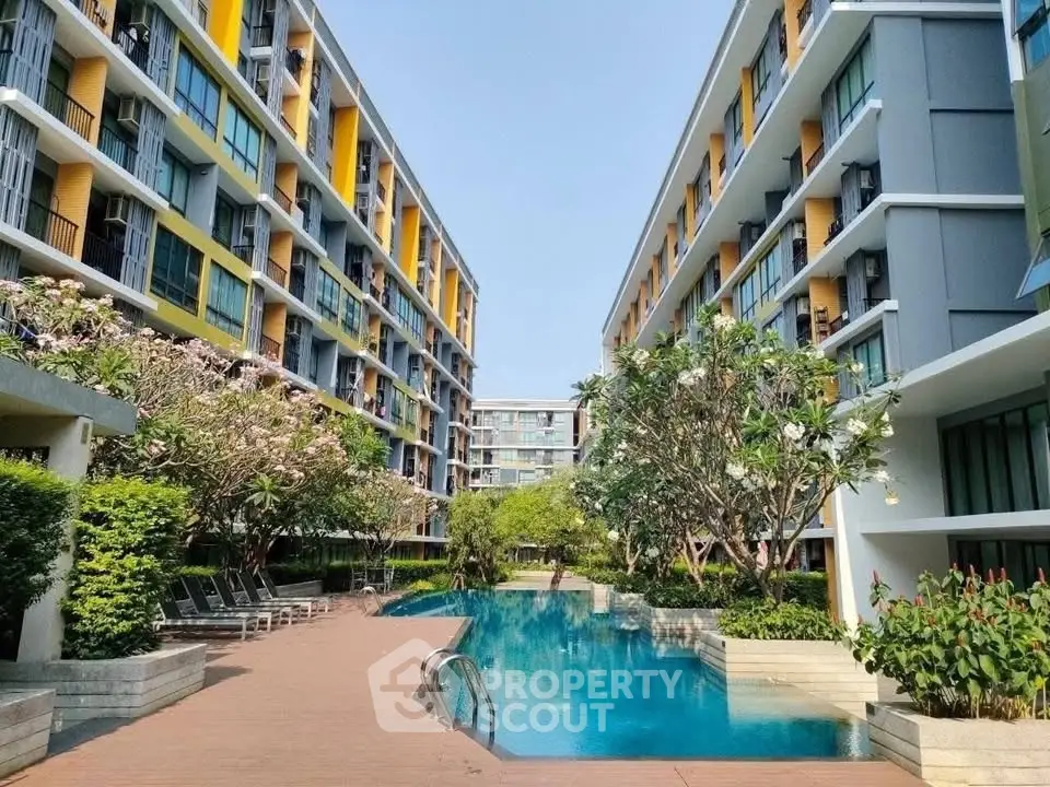 Modern apartment complex with lush greenery and inviting swimming pool