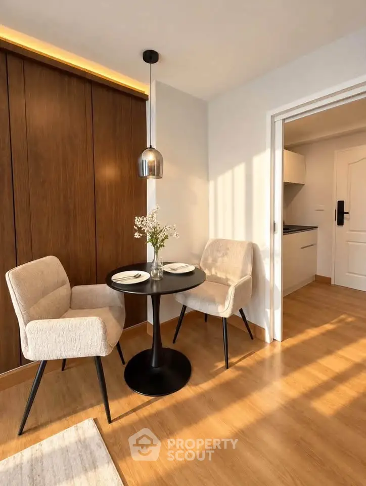 Cozy dining nook with modern chairs and table, adjacent to a sleek kitchen in a sunlit apartment.