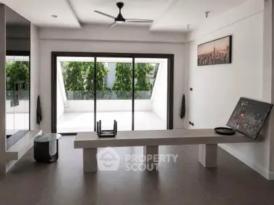 Modern minimalist living room with large sliding glass doors leading to a spacious balcony.