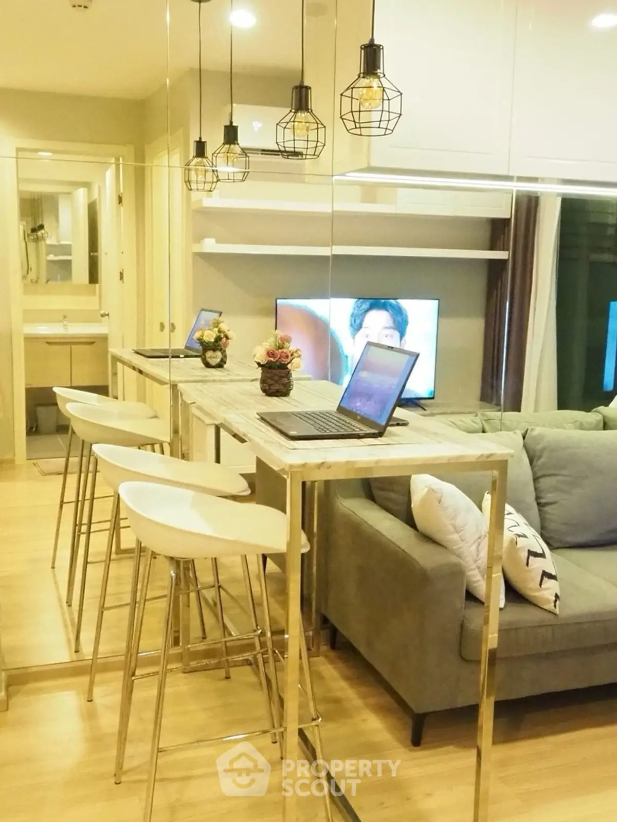 Modern living room with stylish decor and open layout, featuring a cozy sofa and sleek bar stools.