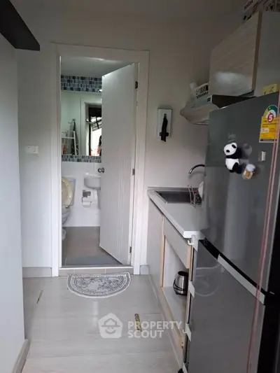Compact kitchen with modern appliances and view into adjacent bathroom.