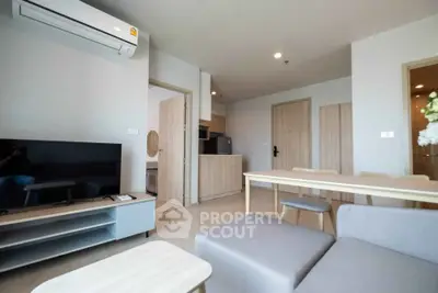 Modern living room with open kitchen, featuring sleek furniture and neutral tones for a cozy ambiance.