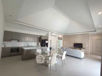 Spacious modern open-plan kitchen and living room with high ceilings and elegant decor.