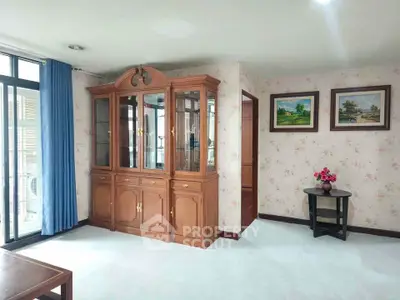 Charming living room with elegant wooden cabinet and floral wallpaper, perfect for cozy gatherings.