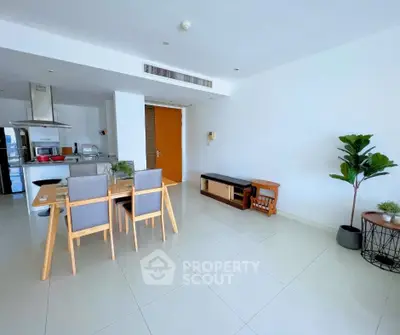 Spacious modern dining area with sleek furniture and open kitchen layout in a bright apartment.