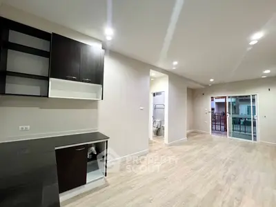 Spacious open-plan living area with modern kitchen and sliding glass doors leading to balcony.