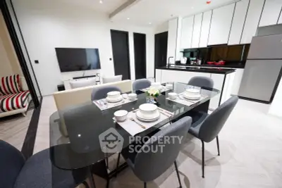 Modern dining area with sleek black table and stylish kitchen in open layout apartment.