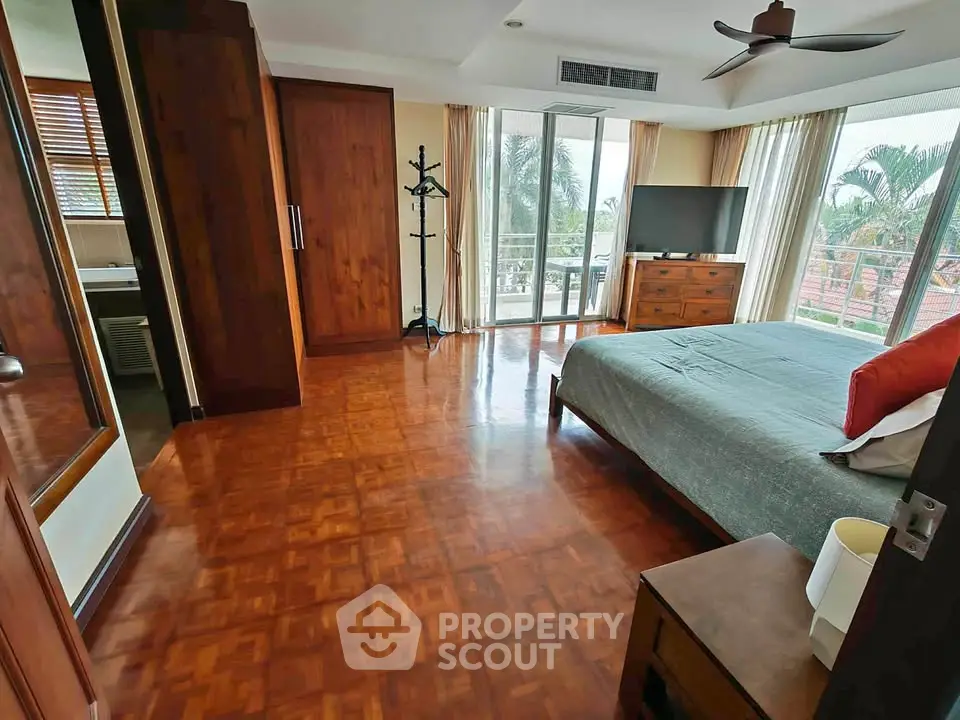 Spacious bedroom with balcony access and large windows offering a scenic view.