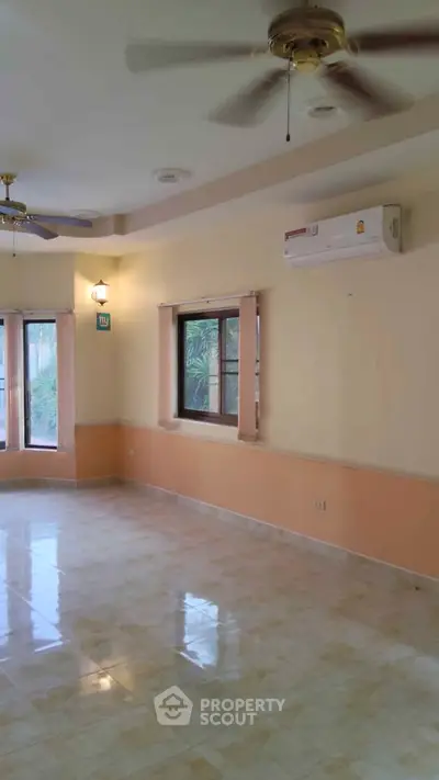 Spacious living room with ceiling fans and air conditioning, featuring large windows for natural light.