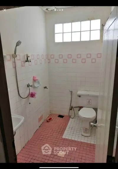 Charming vintage bathroom with pink tile accents and natural light, perfect for a cozy home renovation.