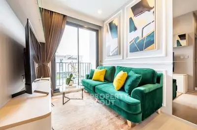 Modern living room with green velvet sofa, abstract art, and balcony view in a stylish apartment.