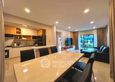 Spacious open-plan living room and kitchen with modern furnishings and large windows.