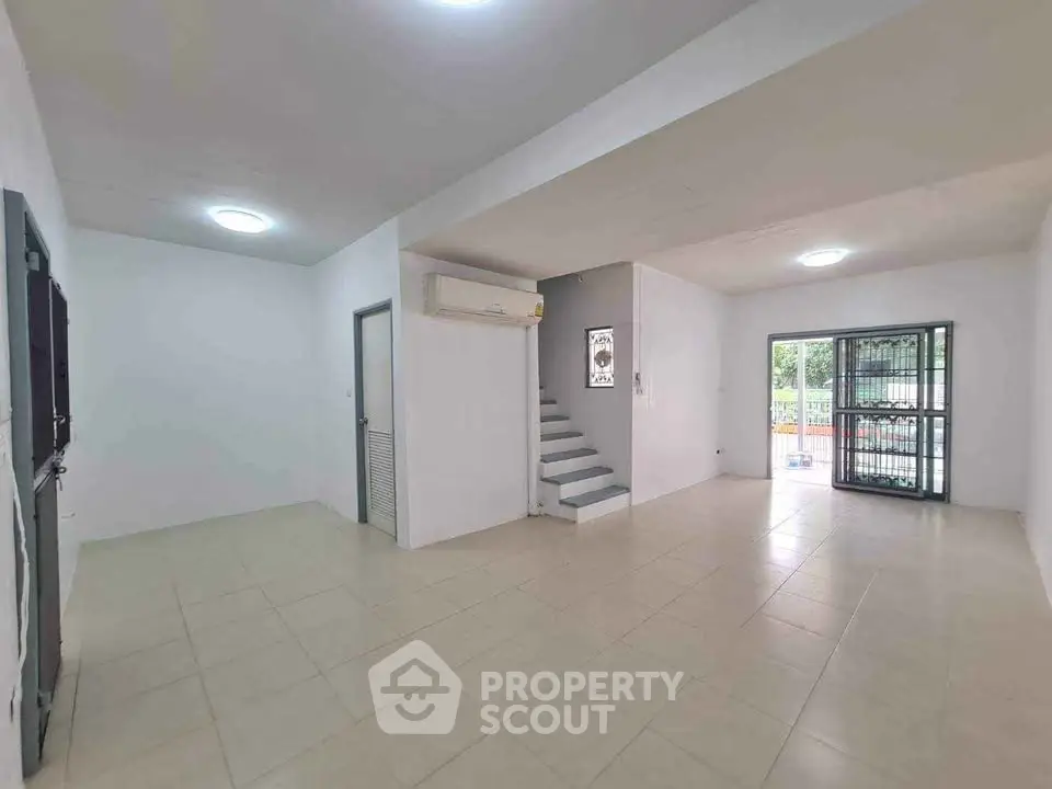 Spacious open-plan living area with modern tiled flooring and natural light.