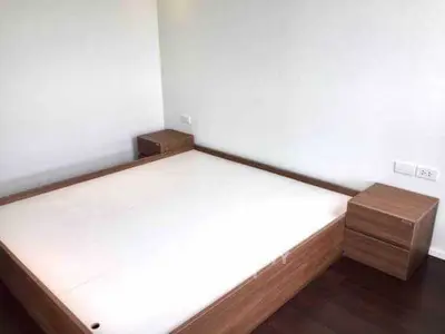 Spacious minimalist bedroom with wooden bed frame and side tables.