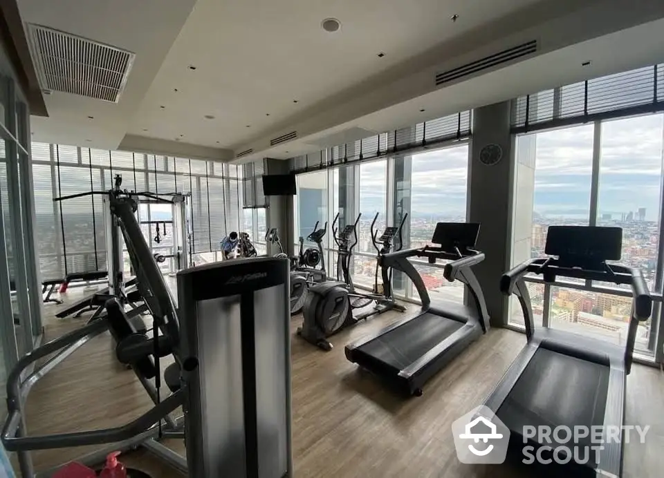 Luxurious high-rise gym with panoramic city views and modern fitness equipment.