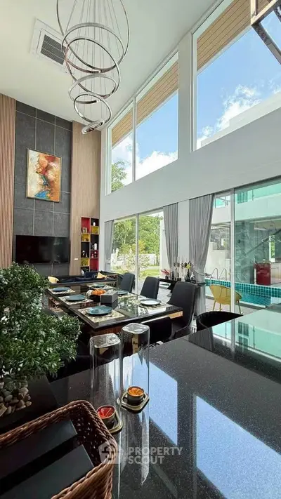 Luxurious modern living room with high ceilings and large windows overlooking a pool, featuring elegant decor.