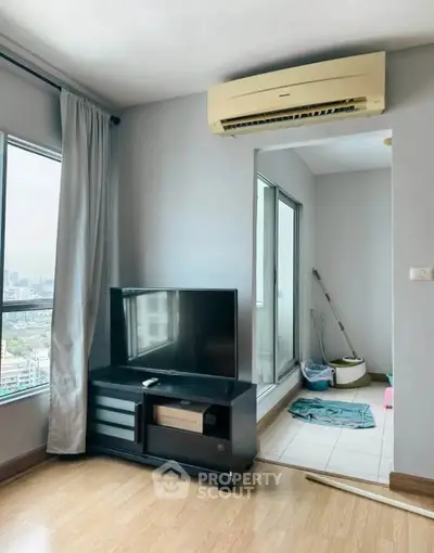 Modern living room with city view, featuring sleek TV setup and air conditioning.