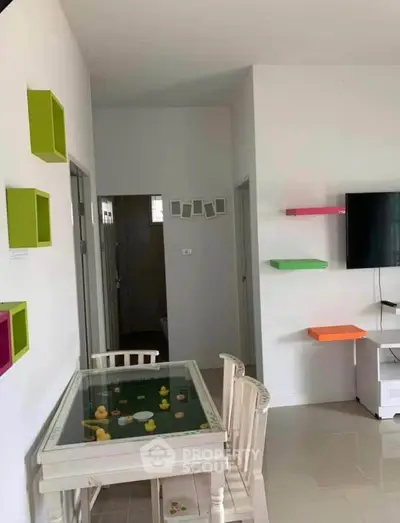 Charming living room with colorful wall shelves and a unique glass-top table, perfect for modern family living.