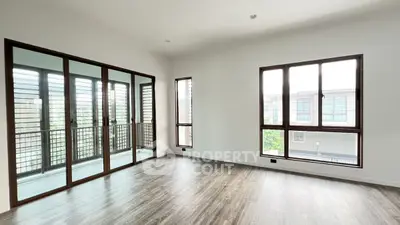 Spacious empty room with large windows and sliding glass doors leading to a balcony.