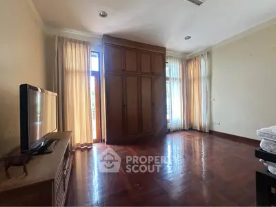 Spacious bedroom with wooden flooring and large windows for natural light.