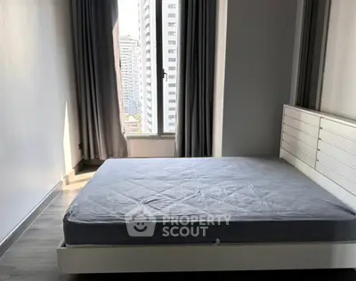 Modern bedroom with large window and city view, featuring sleek design and natural light.