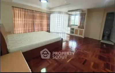 Spacious bedroom with wooden flooring and large windows for natural light
