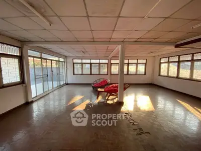 Spacious sunlit room with large windows and unique seating, perfect for versatile use.