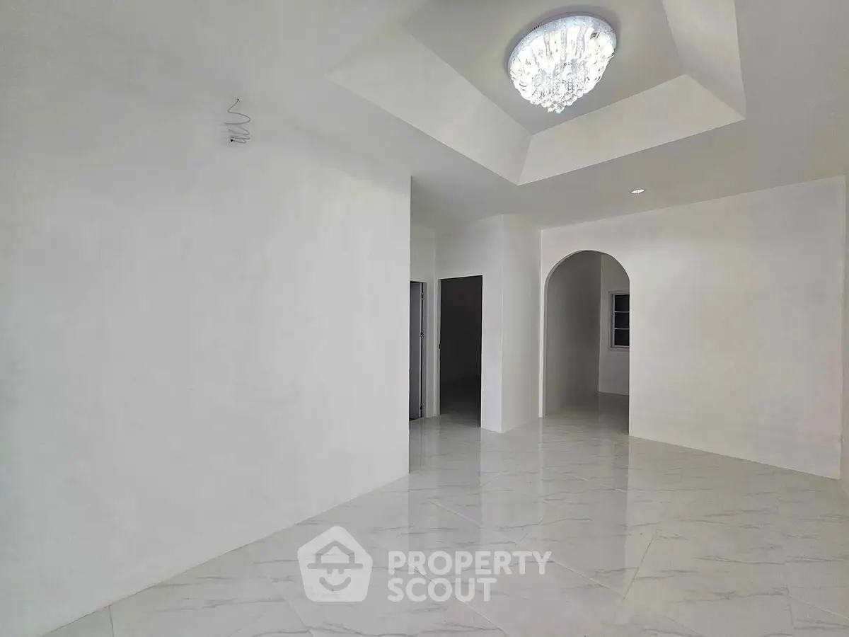 Spacious white interior with elegant ceiling light and archway