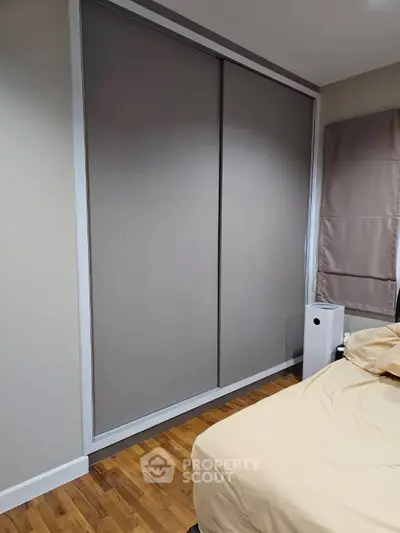 Modern bedroom with sliding wardrobe and wooden flooring