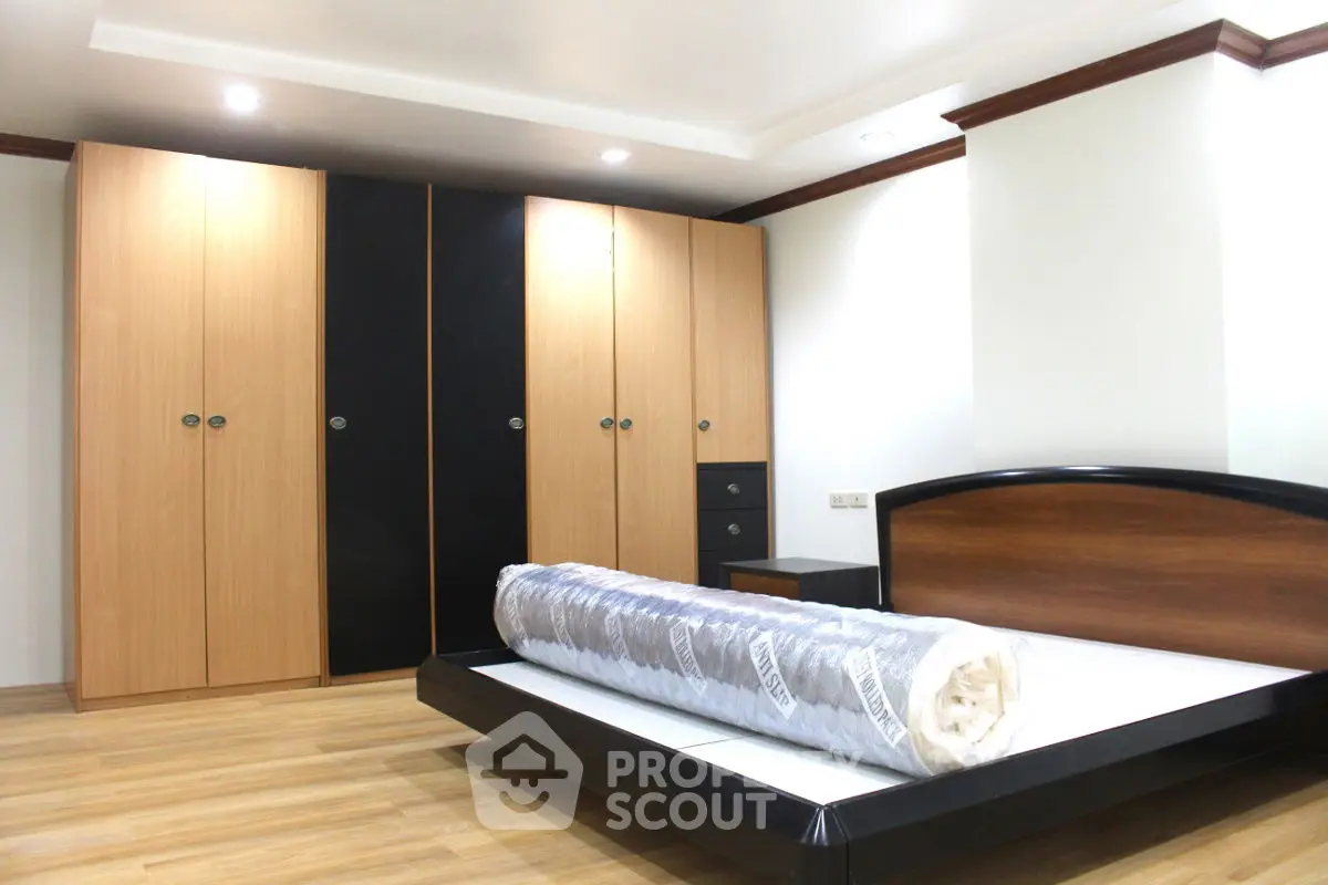 Spacious bedroom with modern wooden wardrobe and sleek bed frame.