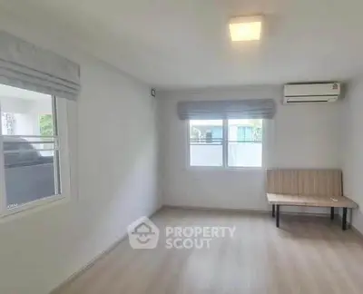 Spacious living room with natural light and modern air conditioning unit.