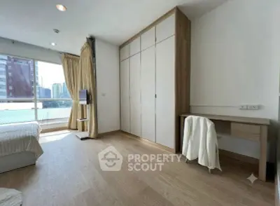Spacious bedroom with large window and built-in wardrobe in modern apartment