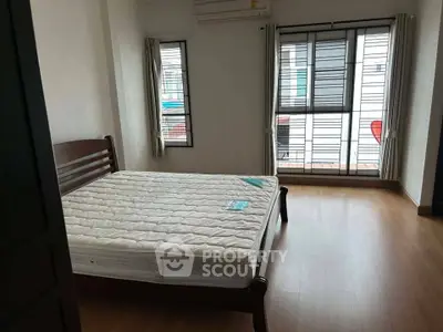 Spacious bedroom with large windows and wooden flooring