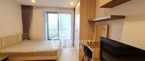 Modern bedroom with balcony view, featuring stylish furniture and ample natural light.