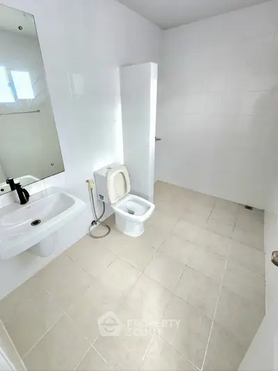Spacious modern bathroom with sleek white tiles and contemporary fixtures.