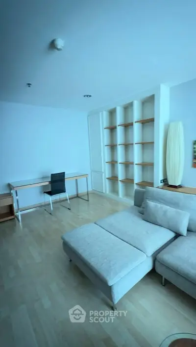 Spacious living room with modern furniture and built-in shelves, perfect for relaxation and productivity.