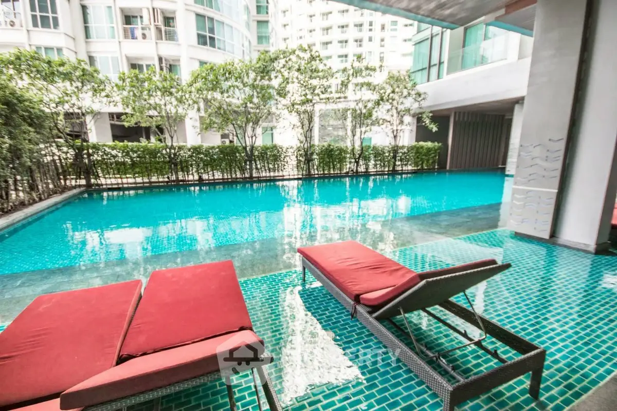 Luxurious apartment complex with a stunning outdoor pool and modern lounge chairs.