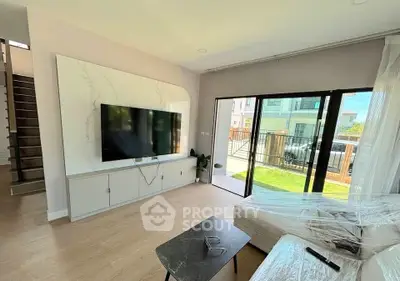 Modern living room with large TV and sliding glass doors to balcony